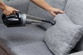 Employee cleaning sofa with vacuum cleaner