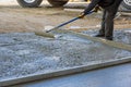 An employee of a construction company leveled a wet concrete sidewalk with the use of long trowels after pouring