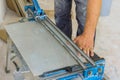 An employee of construction company uses a tile cutting hand machine to cut ceramic tiles.