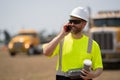 employee construction man in vest protective hardhat, copy space. mature architect in construction area has phone call