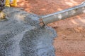 An employee at a construction site is pouring wet concrete into a driveway that is paving over a near new house. Royalty Free Stock Photo