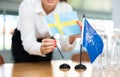 Employee of delegation prepares negotiating table - sets up flag of NATO & x28;OTAN& x29; and Sweden