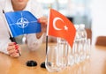 Employee of delegation prepares negotiating table - sets up flag of NATO (OTAN) and Turkey