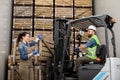 Employee on electric forklift carry container with ripe apples to storage camera, manager with tablet shows direction