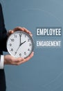 Employee engagement concept represented by hands holding a clock on a blue background Royalty Free Stock Photo