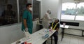 An employee in a factory is having an antigen test carried out by a qualified health worker and wearing a protective suit