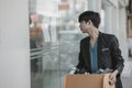 An employee fired or resigned from a company is holding a box reading a job posting in front of the company.. Unemployed, hiring Royalty Free Stock Photo