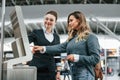 Employee helping to use terminal. Young female tourist is in the airport at daytime