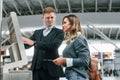 Employee helping to use terminal. Young female tourist is in the airport at daytime