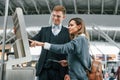 Employee helping to use terminal. Young female tourist is in the airport at daytime