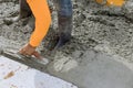 An employee is holding a steel trowel as he smooths leveling over a freshly poured concrete sidewalk in the construction Royalty Free Stock Photo