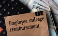 EMPLOYEE MILEAGE REIMBURSEMENT - words on brown paper on the background of calculator and banknotes