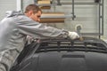 An employee of the paint shop of the automobile plant prepares bumpers for painting