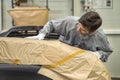 An employee of the paint shop of the automobile plant prepares bumpers for painting