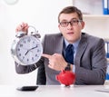 Employee with piggybank in time management concept Royalty Free Stock Photo