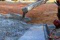 An employee is pouring wet concrete at a new construction site on the site of a near new home in order to pave a Royalty Free Stock Photo