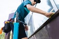 An employee of a professional cleaning service in overalls washes the facade and windows with special devices