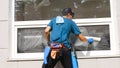 An employee of a professional cleaning service in overalls washes the glass of the windows of the facade of the building Royalty Free Stock Photo