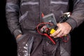 Employee in protective work safety clothing with cable and combination pliers. Occupational safety and health accessories for