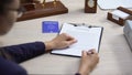Employee signing deportation document holding blue passport, international law