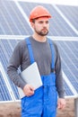 An employee of the solar battery station looks somewhere and holding laptop. Outdoors.