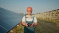 An employee of a solar power plant talks on a walkie-talkie while his colleagues and an investor check the solar power