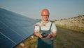 An employee of a solar power plant talks on a walkie-talkie while his colleagues and an investor check the solar power