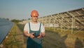 An employee of a solar power plant talks on a walkie-talkie while his colleagues and an investor check the solar power