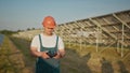 An employee of a solar power plant talks on a walkie-talkie while his colleagues and an investor check the solar power