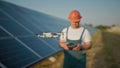 An employee of a solar power plant talks on a walkie-talkie while his colleagues and an investor check the solar power