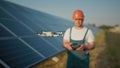 An employee of a solar power plant talks on a walkie-talkie while his colleagues and an investor check the solar power