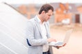 An employee of the solar station holds a laptop, standing next to the solar panel.