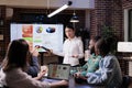 Employee standing in front of team of coworkers presenting sales strategy using remote control Royalty Free Stock Photo