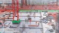 The employee wearing safety uniform working in the construction site with red cranes and steel pillar for build modern