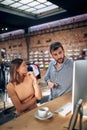 Employees in clothing shop talking in front of desktop computer, brainstorming, working in team on project, looking at screen Royalty Free Stock Photo