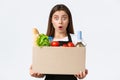 Employees, delivery and online orders, grocery stores concept. Shocked cashier or saleswoman holding box with food and