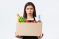 Employees, delivery and online orders, grocery stores concept. Shocked and confused female cashier, saleswoman holding