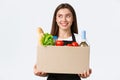 Employees, delivery and online orders, grocery stores concept. Smiling cheerful female courier, saleswoman packed online