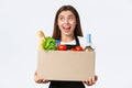 Employees, delivery and online orders, grocery stores concept. Smiling cheerful female courier, saleswoman packed online