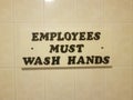 Employees must wash hands sign on white bathroom tile Royalty Free Stock Photo