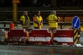 Employees of the road service in special yellow vests perform work on the repair of the roadway. Night road repairs in difficult Royalty Free Stock Photo