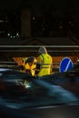 Employees of the road service in special yellow vests perform work on the repair of the roadway. Night road repairs in difficult Royalty Free Stock Photo