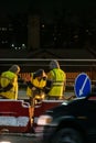 Employees of the road service in special yellow vests perform work on the repair of the roadway. Night road repairs in difficult Royalty Free Stock Photo