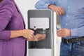 Employees taking glasses of water from cooler in office Royalty Free Stock Photo