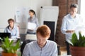 Employees working in shared office focus on busy redhead man Royalty Free Stock Photo
