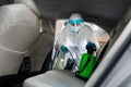 Employer in protective suit with mask disinfecting inside car