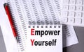 EMPOWER YOURSELF text on notebook with pen, calculator and chart on grey background Royalty Free Stock Photo