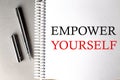 EMPOWER YOURSELF text on a notebook with pen on grey background Royalty Free Stock Photo