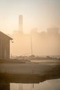 Empty abandoned sail boat club yard shrouded in fog and mist with boats sails and power station cooling tower chimneys Royalty Free Stock Photo