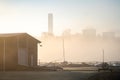 Empty abandoned sail boat club yard shrouded in fog and mist with boats sails and power station cooling tower chimneys Royalty Free Stock Photo